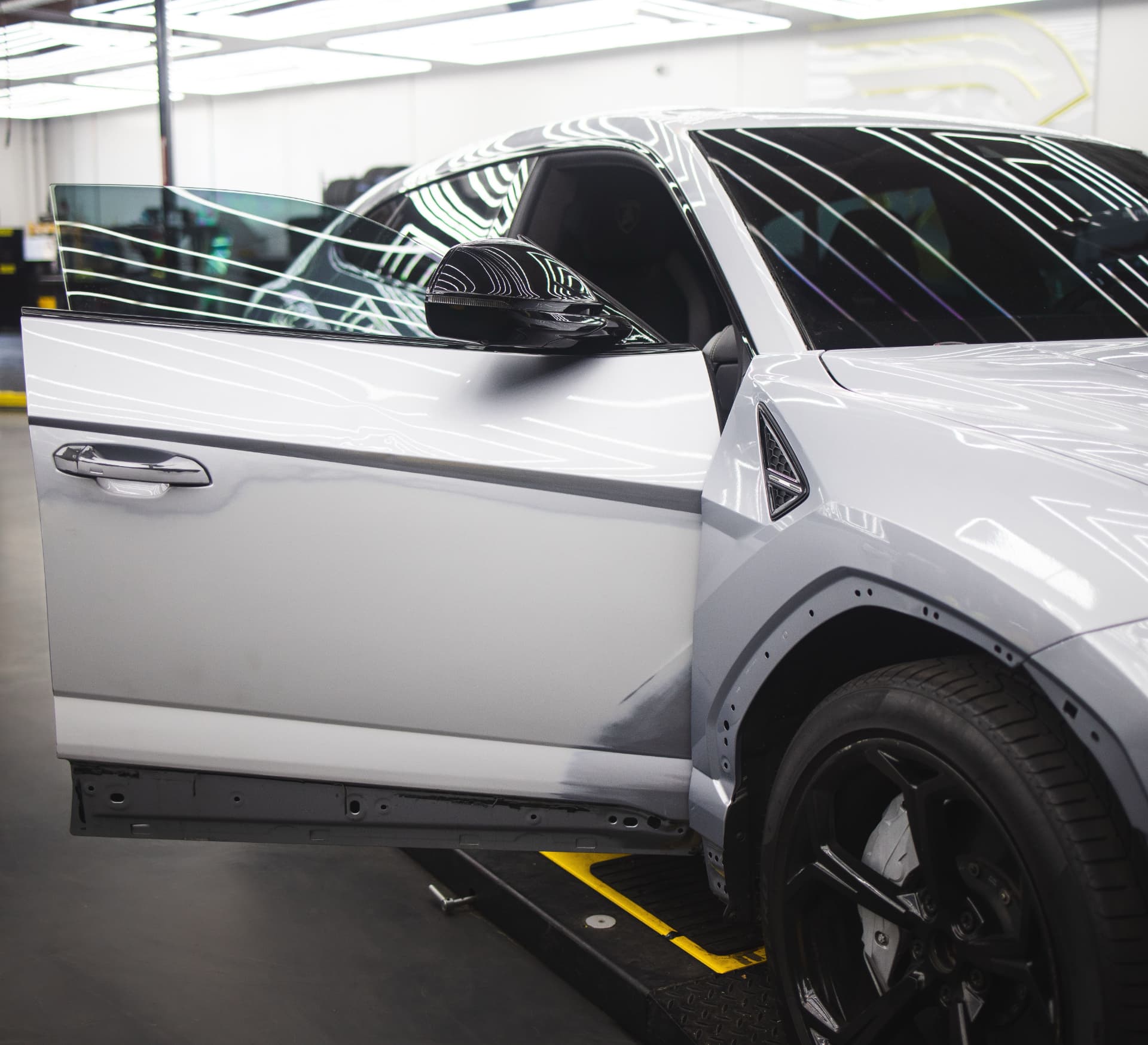 White vehicle undergoing precise auto body repair under professional inspection lighting